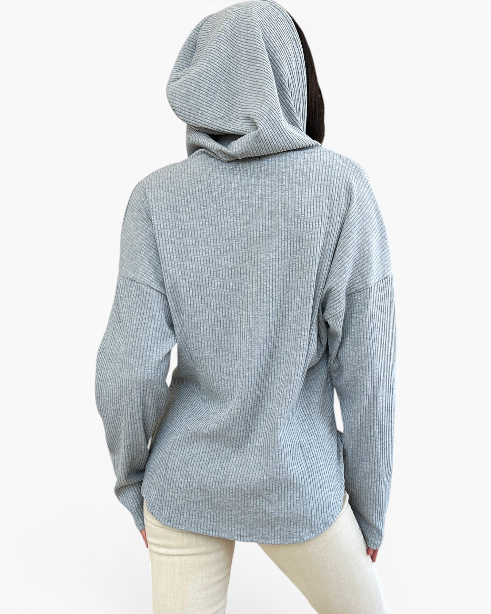 A person shown from the back wearing a light heather gray ribbed hoodie and cream pants against a plain white studio background.