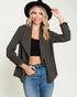 Woman wearing a black blazer, black top, and blue jeans with a black hat on a white background