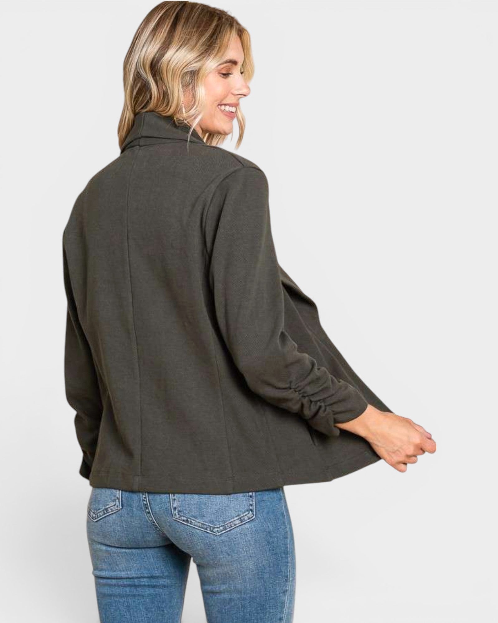 Woman wearing a dark green jacket and blue jeans on a white background