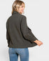 Woman wearing a dark green jacket and blue jeans on a white background