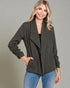 Woman wearing a dark green jacket and blue jeans on a gray background