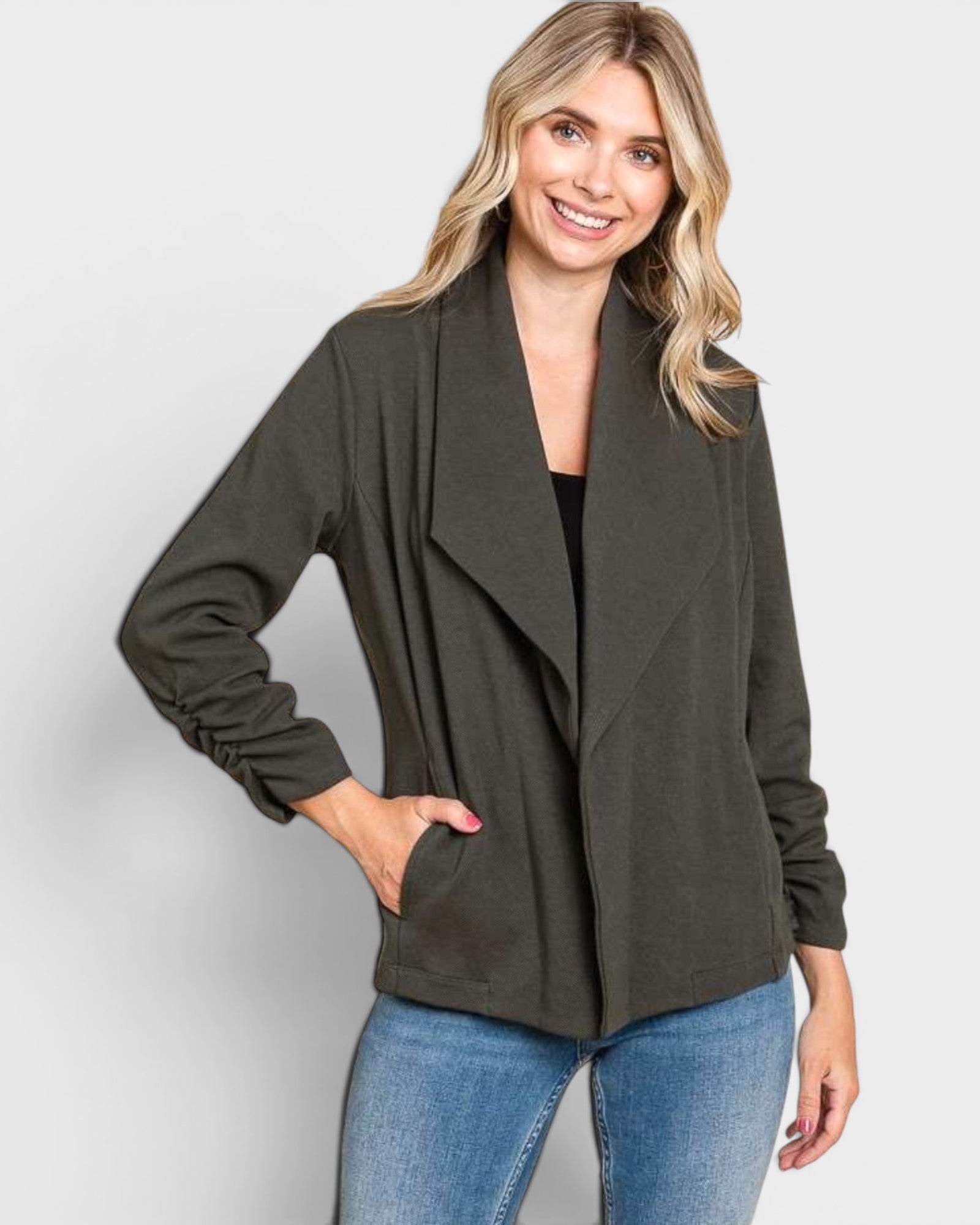 Woman wearing a dark green cardigan and blue jeans on a light gray background