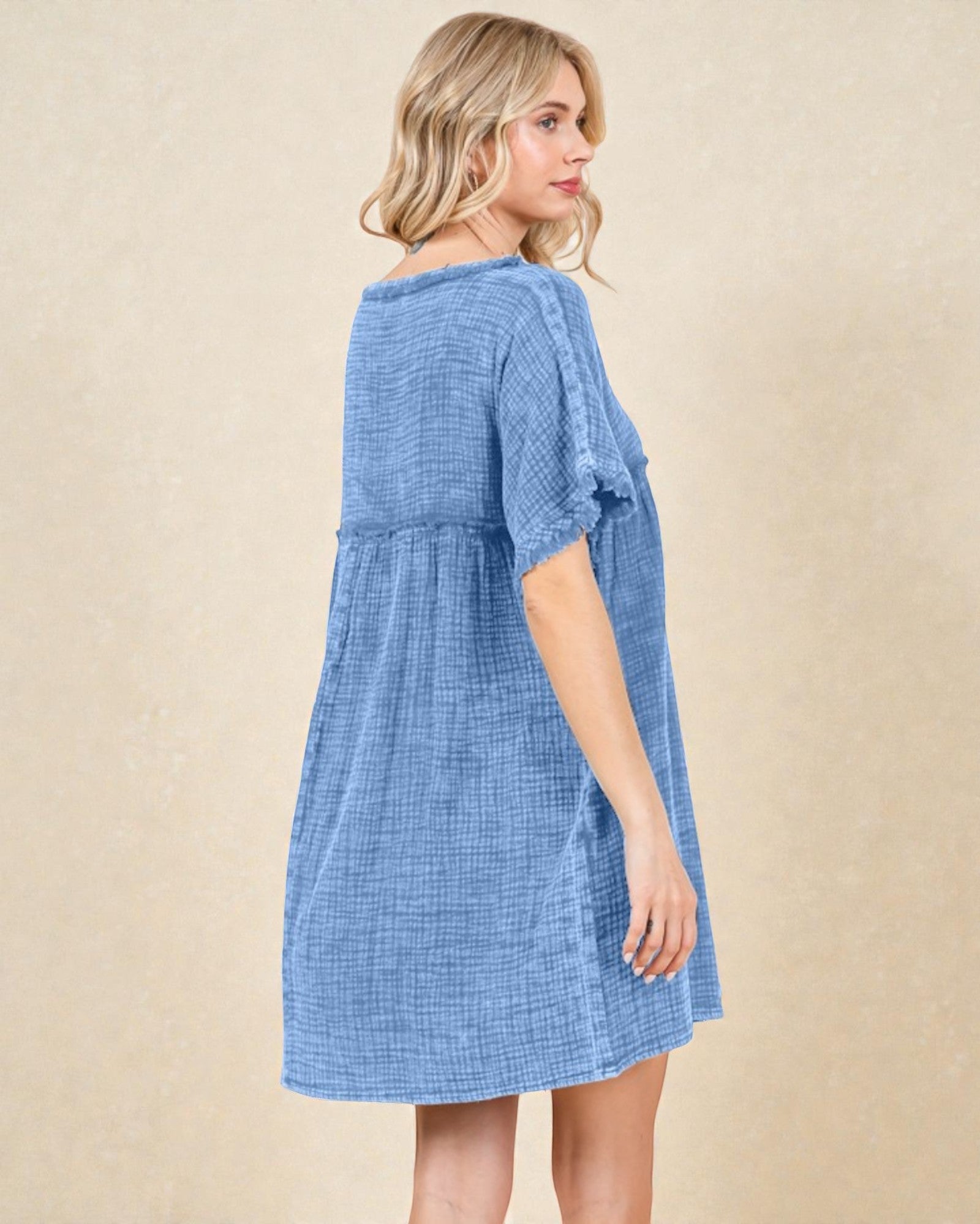 Woman wearing a blue checkered dress against a beige background