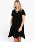 A woman modeling a short-sleeve black dress with a split neckline and button detail, photographed against a plain light gray studio background.