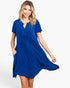 A woman modeling a short-sleeve, knee-length blue dress with a split neckline and side pockets, photographed against a clean white studio background.