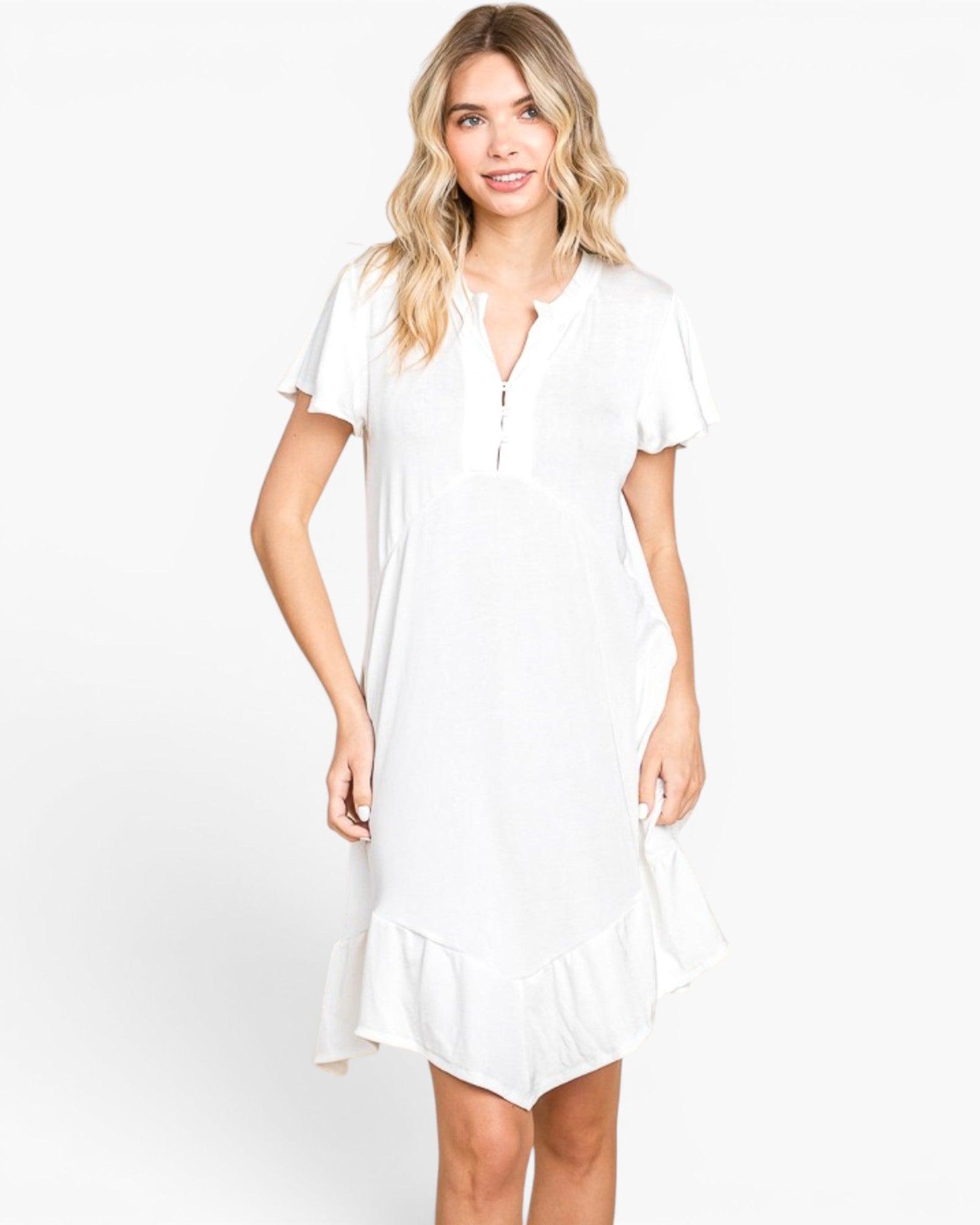A woman modeling a white short-sleeve dress with a split V-neckline and a ruffled hem, set against a plain white studio background.