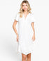 A woman modeling a white short-sleeve dress with a split V-neckline and a ruffled hem, set against a plain white studio background.
