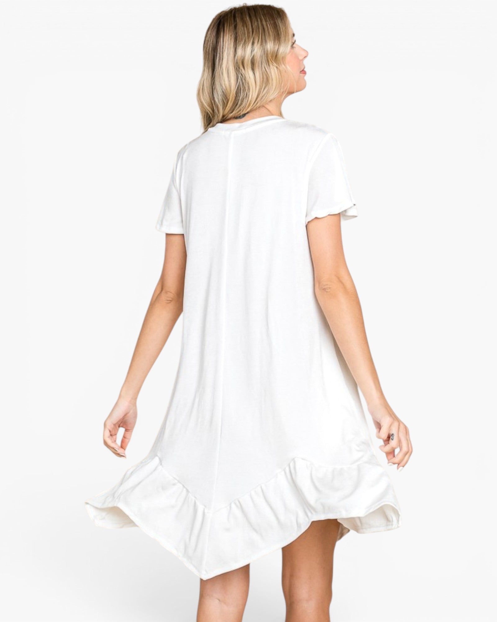 A woman shown from the back wearing a white short-sleeve dress with a ruffled hem, photographed against a plain light gray studio background.