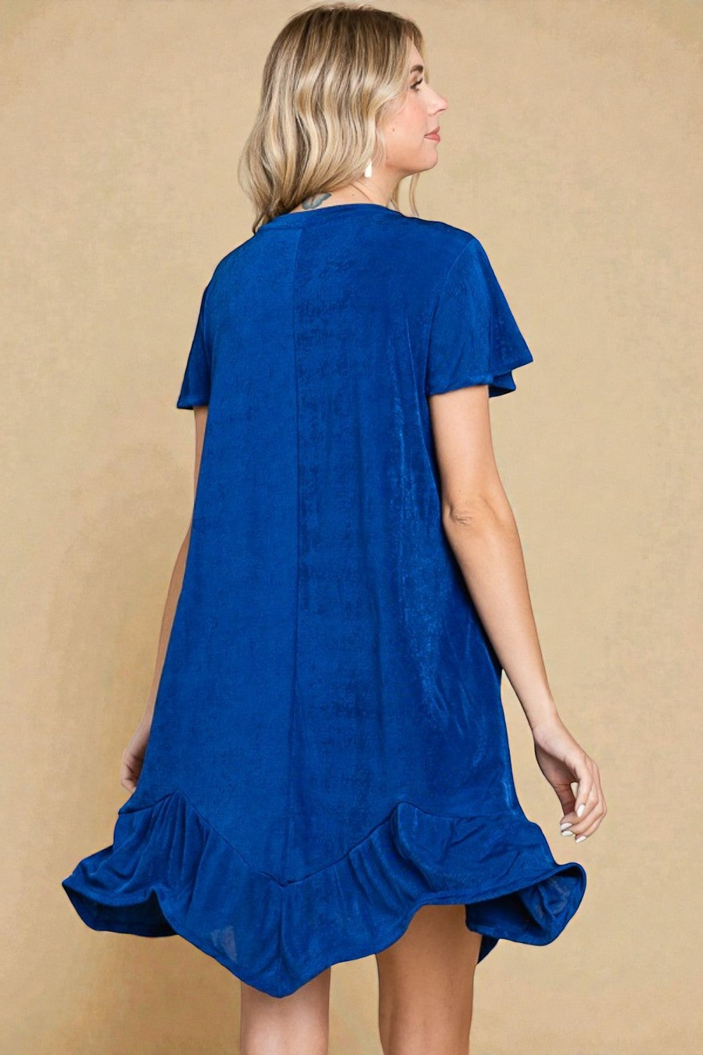 Woman wearing a blue dress with ruffled details on a beige background