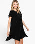 A woman modeling a short-sleeve black velvet dress with a ruffled hem and buttoned neckline against a plain white studio background.