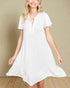 Woman wearing a white dress against a beige wall