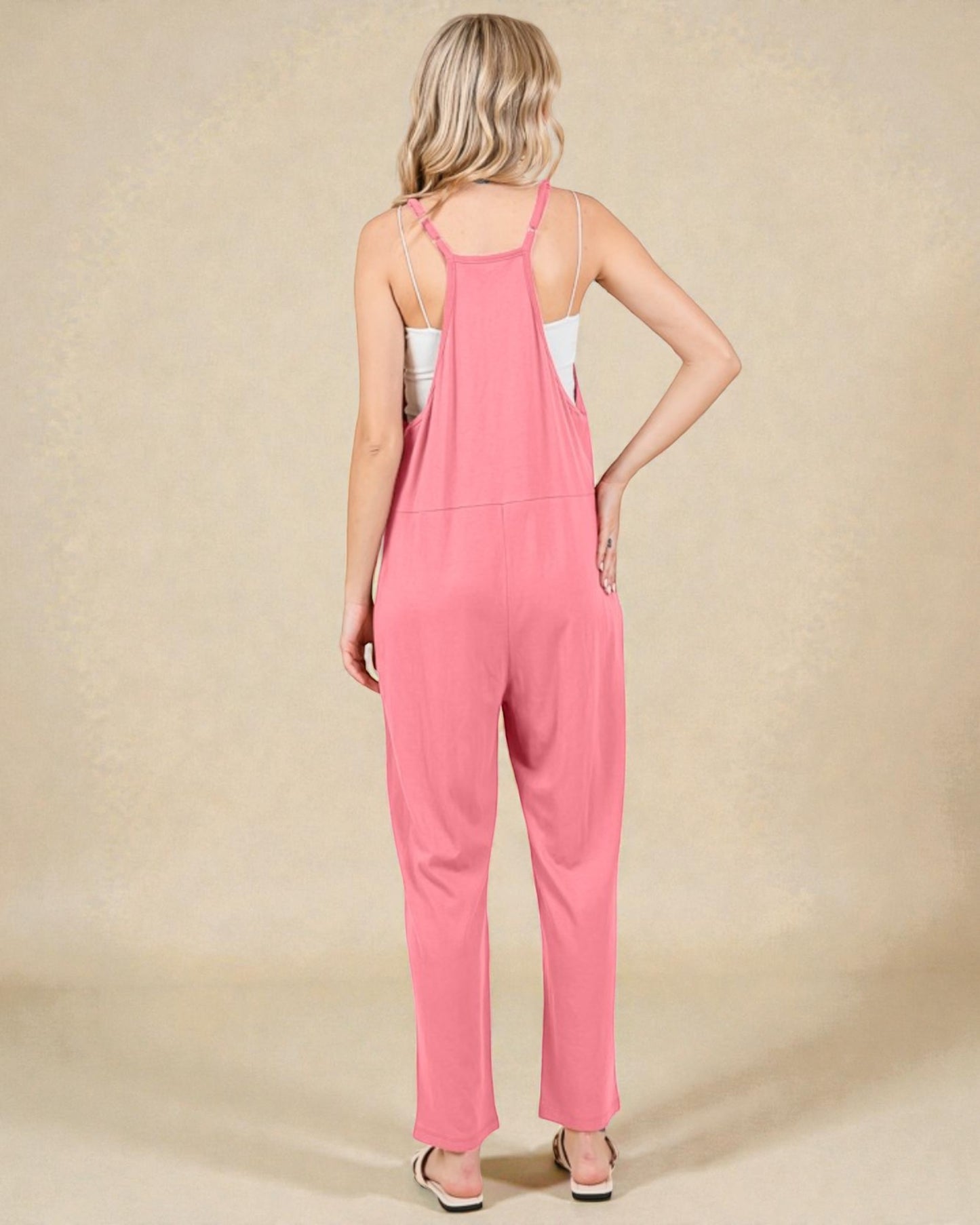 Woman wearing a pink jumpsuit on a beige background