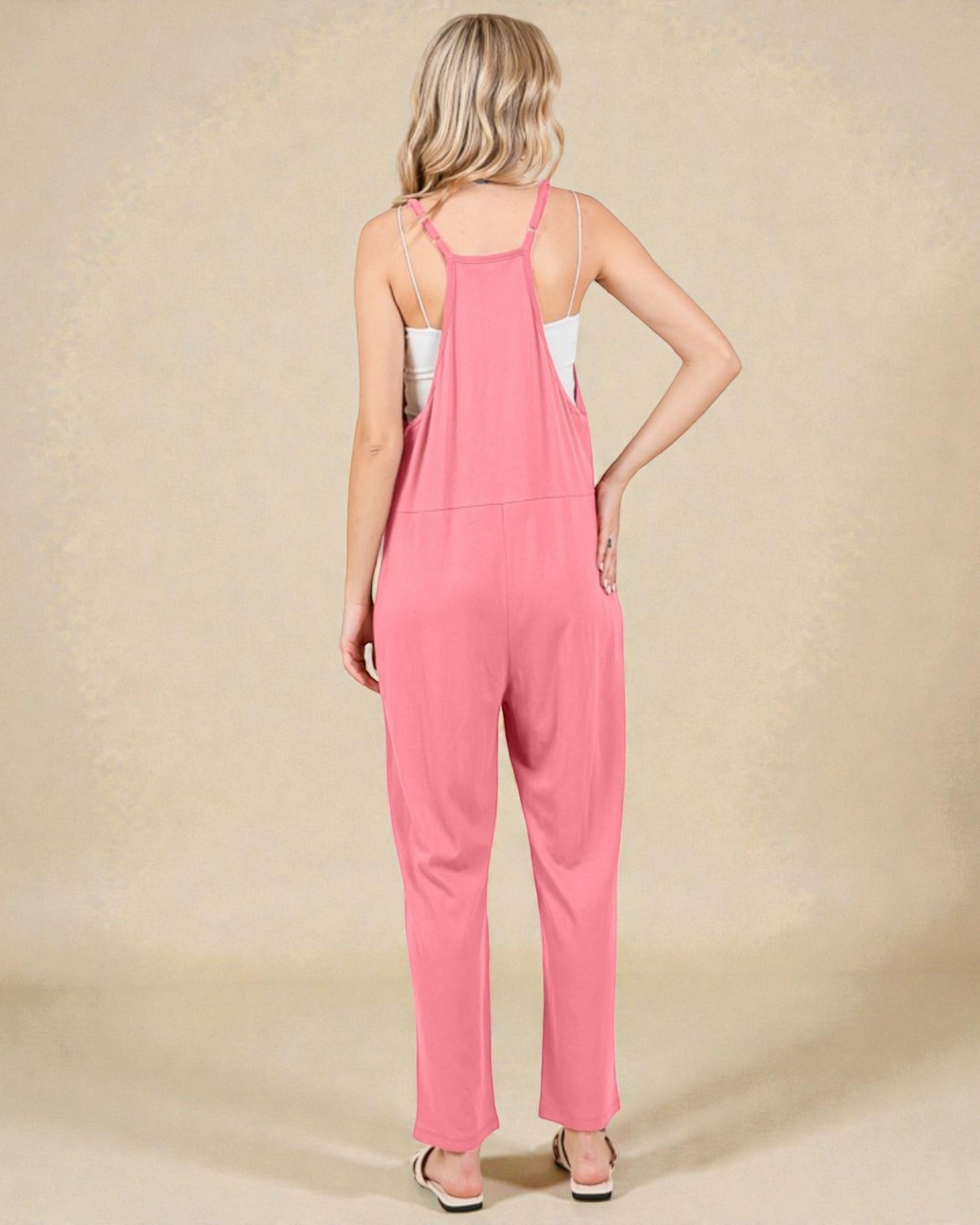 Woman wearing a pink jumpsuit on a beige background