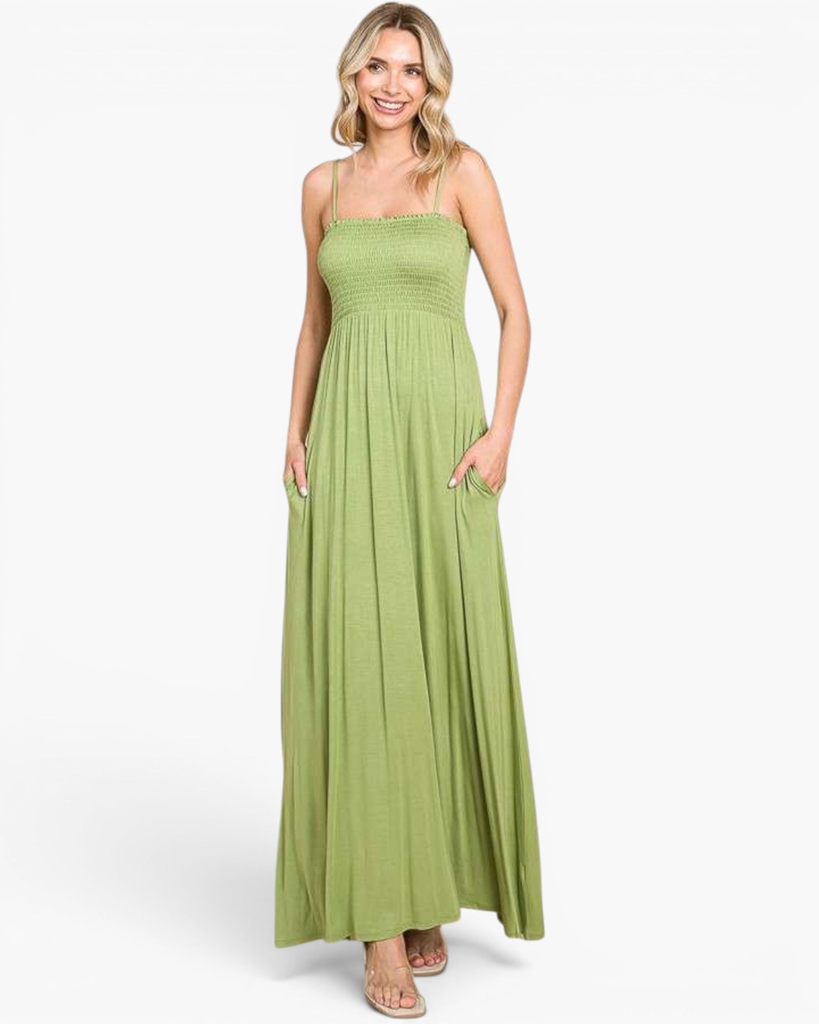 A woman modeling a sleeveless, smocked, and floor-length lime green maxi dress with side pockets, set against a plain white studio background.