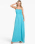 A woman modeling a bright turquoise blue maxi dress with thin spaghetti straps, a smocked bodice, and a flowing skirt, set against a plain white studio background.