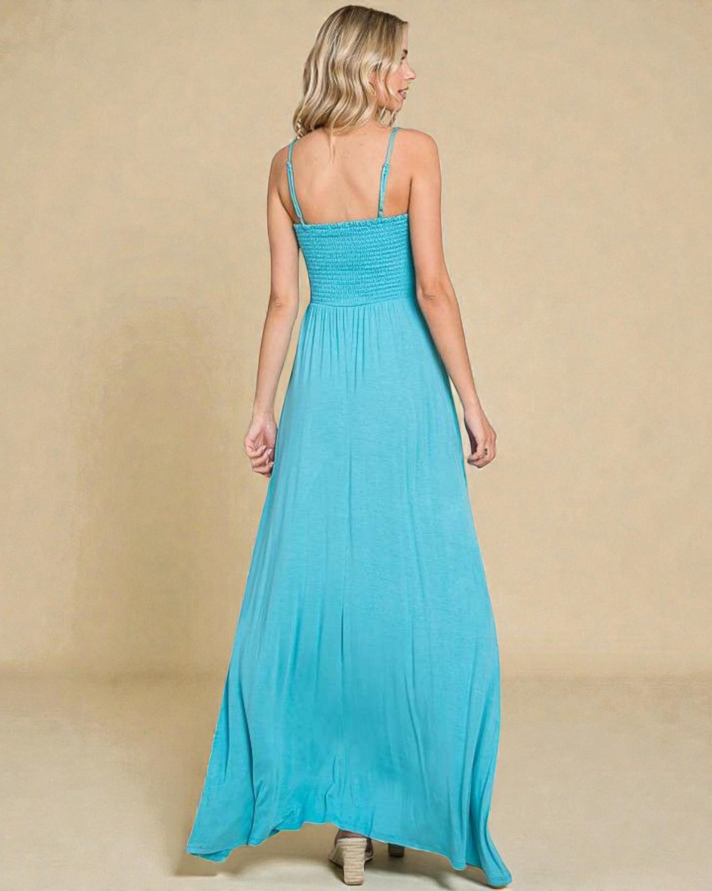 Woman wearing a turquoise maxi dress against a beige background
