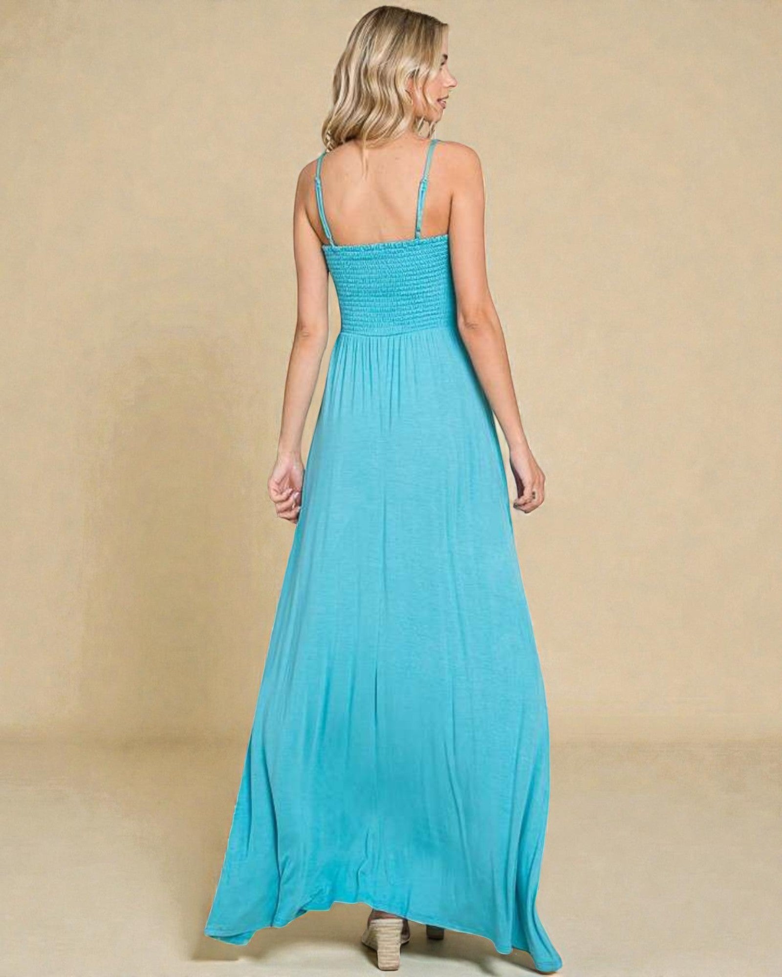 Woman wearing a turquoise maxi dress against a beige background