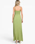 A woman viewed from the back wearing a sage green maxi dress with thin spaghetti straps, a smocked bodice, and a flowing skirt, paired with beige high-heeled sandals against a light gray studio background.