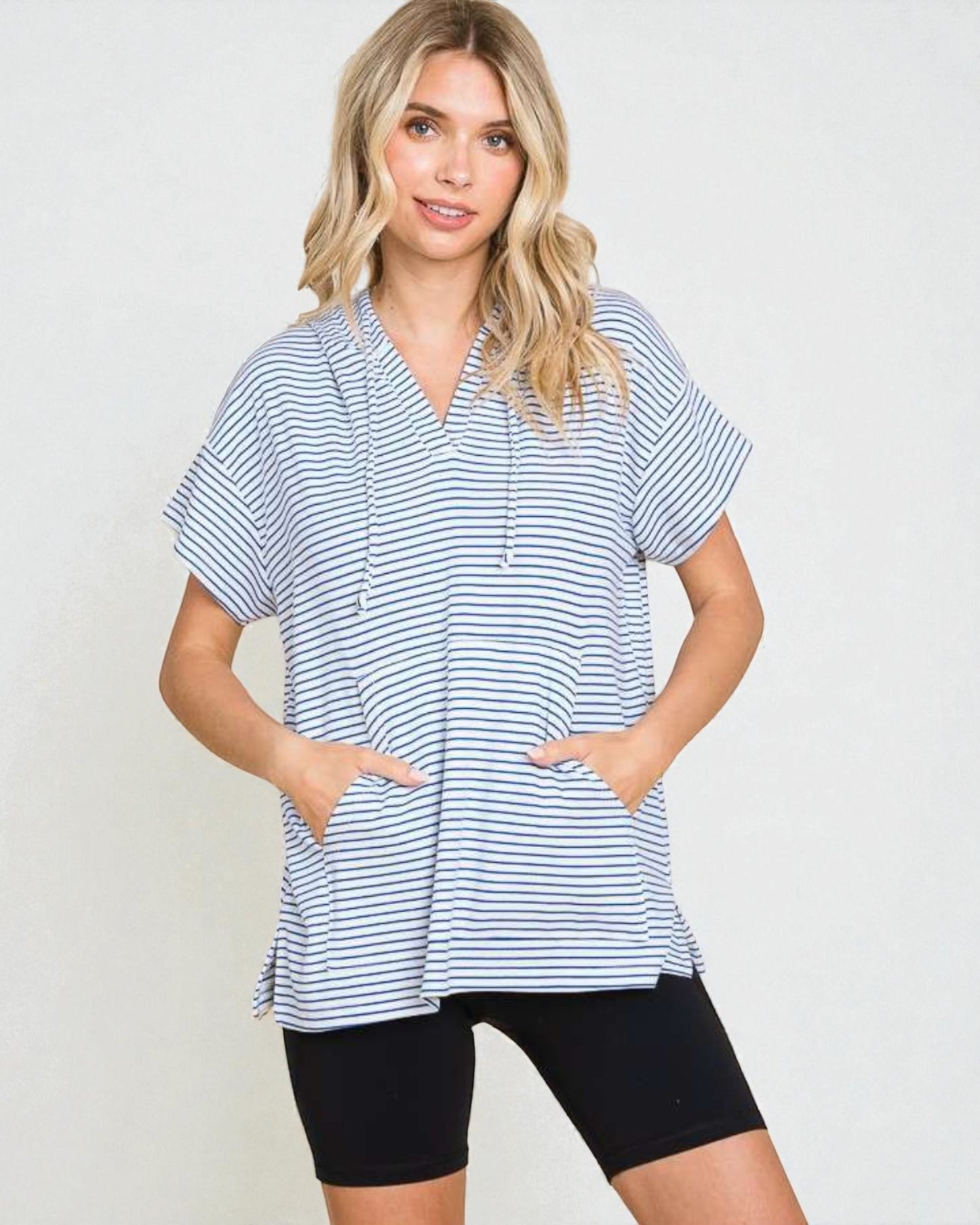 Woman wearing a blue and white striped shirt and black shorts on a plain background