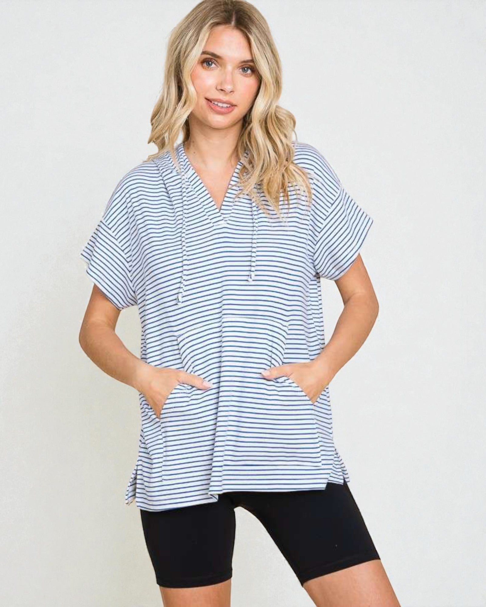 Woman wearing a blue and white striped shirt and black shorts on a plain background