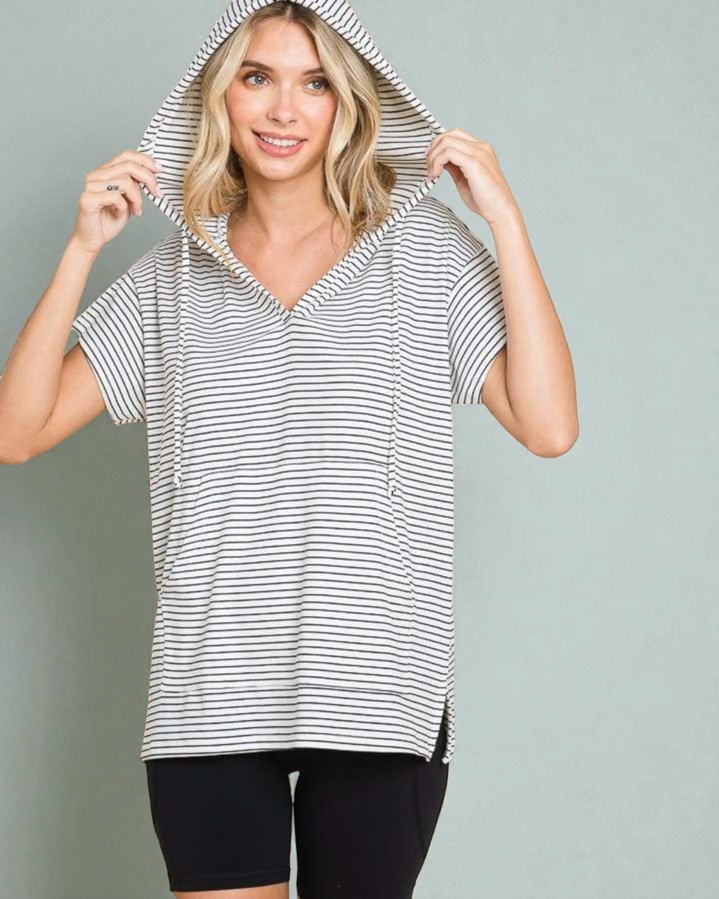 Woman wearing a black and white striped hoodie against a plain background