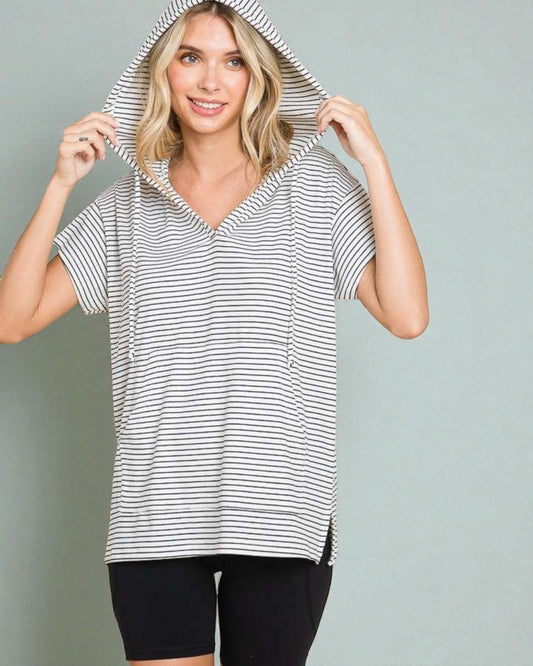 Woman wearing a black and white striped hoodie against a plain background