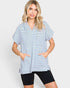 A woman modeling a short-sleeve striped tunic top with drawstrings and front pockets, paired with black bike shorts, against a light gray studio background.