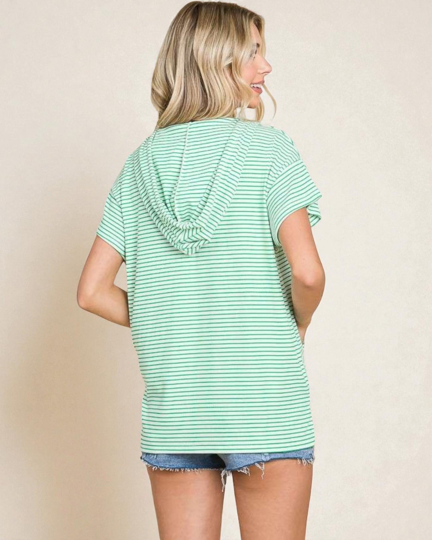 Woman wearing a light green striped hoodie against a beige background