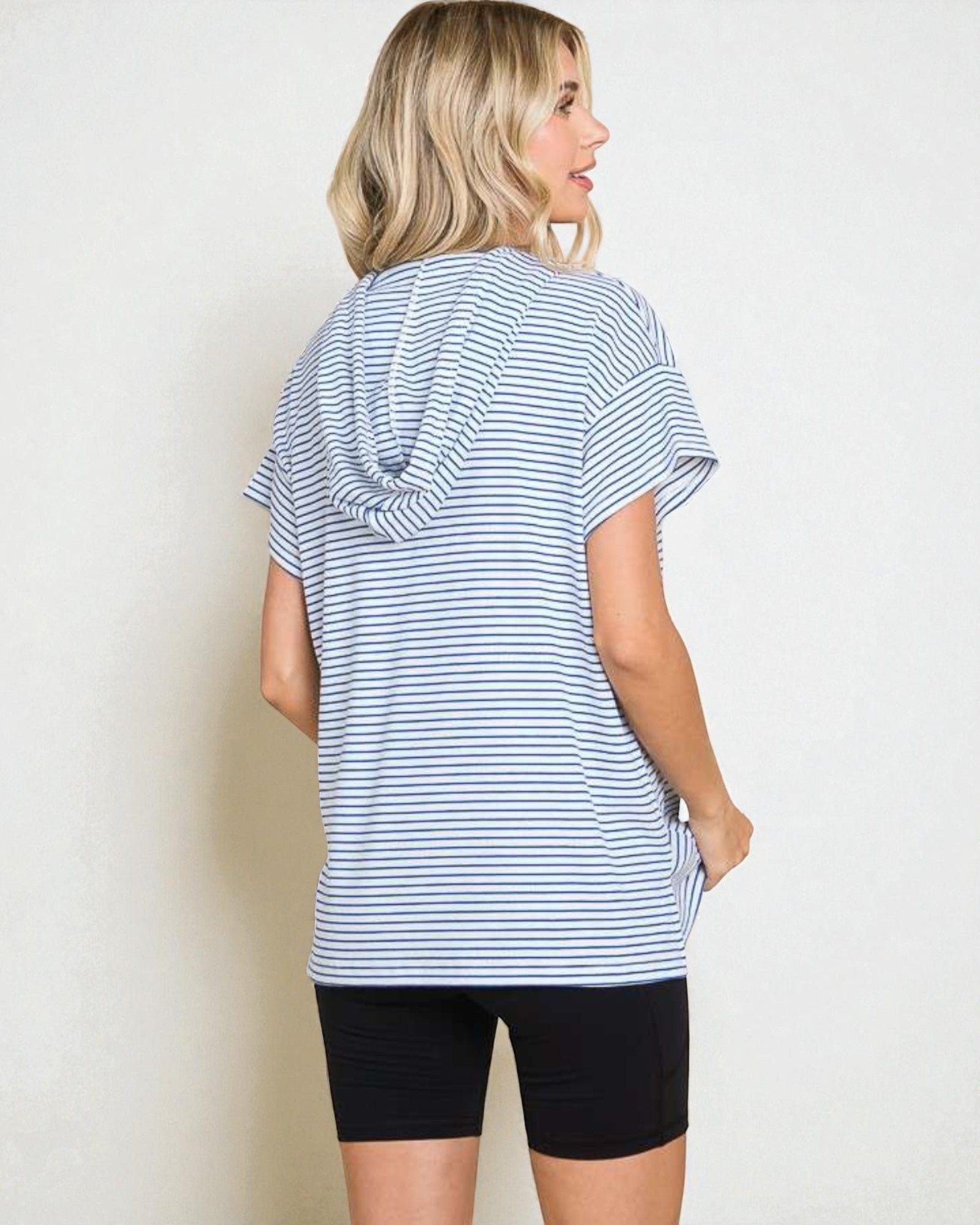 Woman wearing a blue and white striped t-shirt and black shorts on a plain background