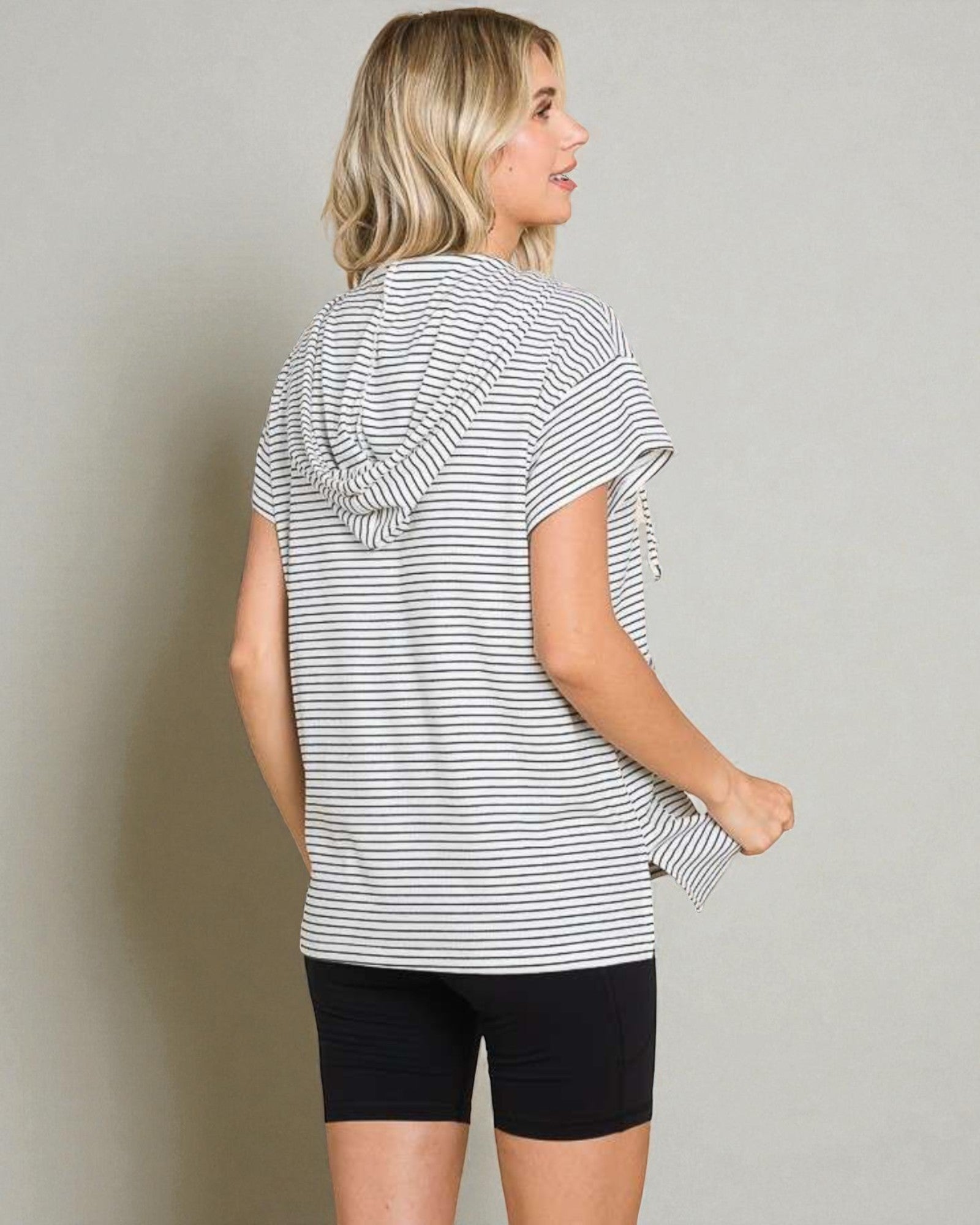 Woman wearing a striped shirt and black shorts against a plain background