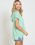 Woman wearing a green and white striped shirt with denim shorts on a plain background
