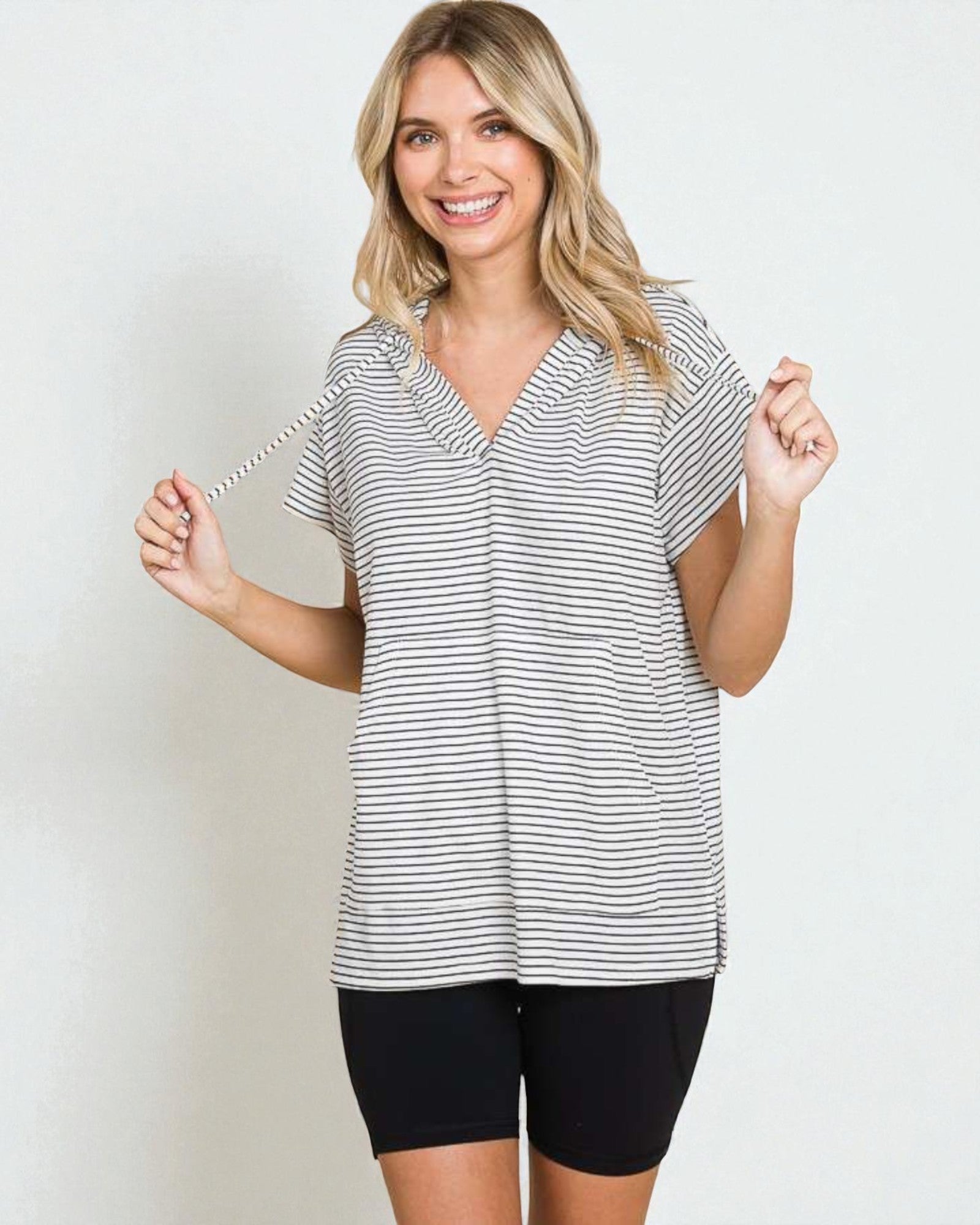 Woman wearing a striped shirt and black shorts on a plain background