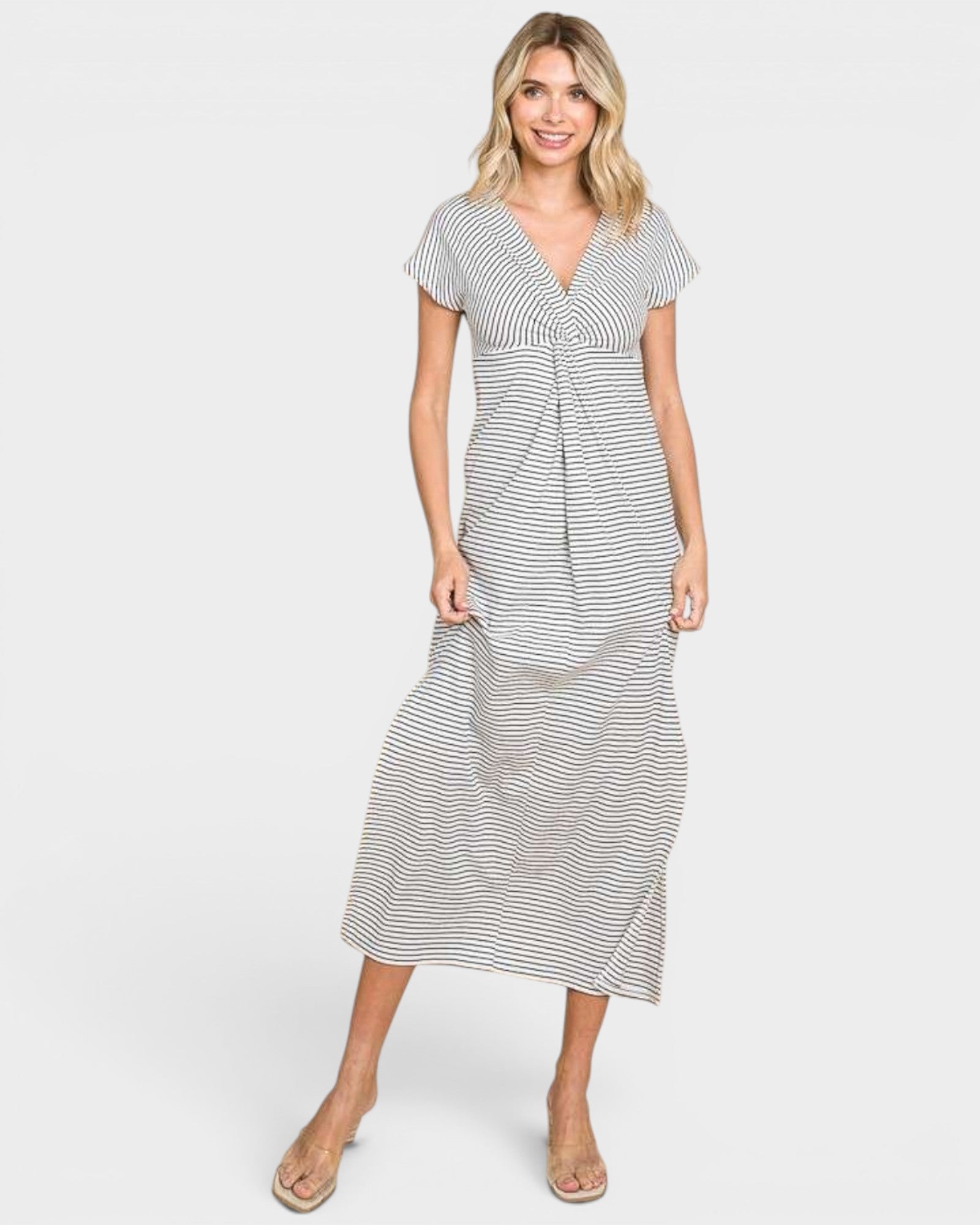A woman modeling a short-sleeve midi dress with a black and white horizontal stripe pattern, featuring a V-neckline and a gathered waist detail, set against a plain light gray background.