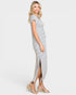 A woman modeling a short-sleeve, knee-length dress with thin black horizontal stripes on a white background, paired with clear wedge sandals, against a light gray studio backdrop.