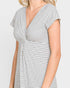 A close-up of a woman wearing a white short-sleeve dress with thin black vertical stripes, featuring a V-neckline and a gathered waist detail.