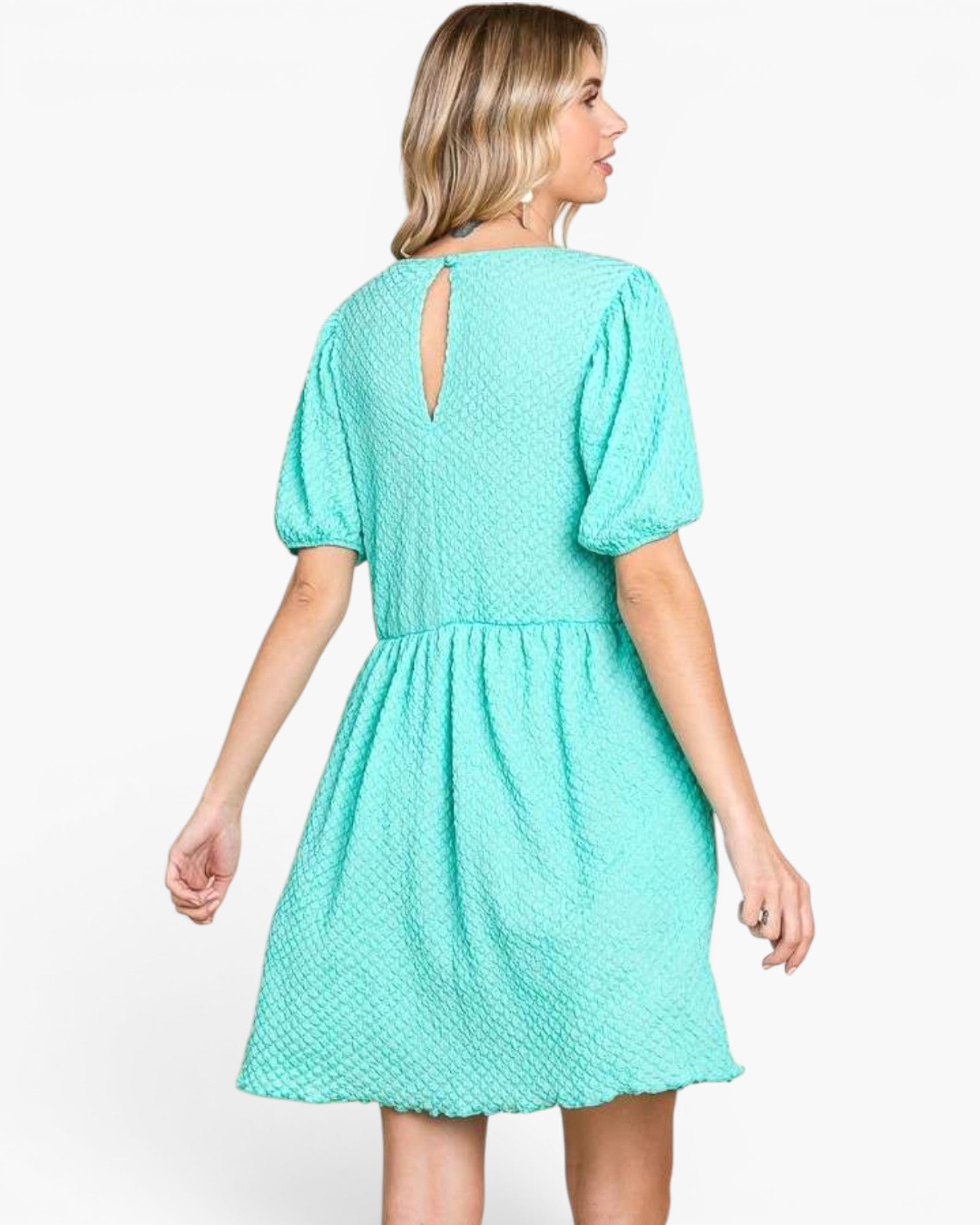 A woman wearing a short-sleeve mint green dress with puff sleeves and a small keyhole back cutout, shown from the back against a plain white background.