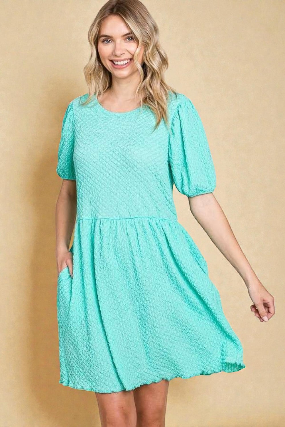 Woman wearing a teal dress against a beige background