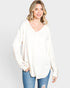Woman wearing a white oversized sweater with a plain background