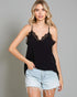 Woman wearing a black lace-trimmed top and denim shorts on a gray background