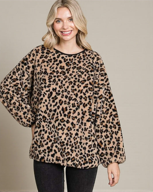 Woman wearing a leopard print sweater against a plain background