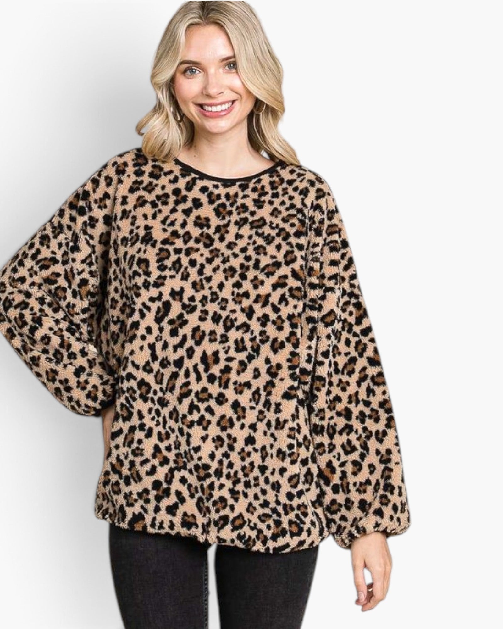 A woman wearing a beige and black leopard print long-sleeve top with black pants, standing against a light gray background.