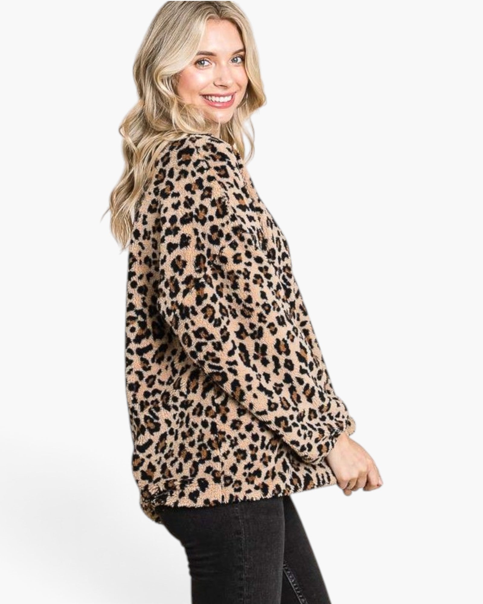 A woman wearing a beige and black leopard print fuzzy fleece jacket, shown from a side-back angle against a plain white studio background.