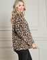 Woman wearing a leopard print sweater in front of a white wall.