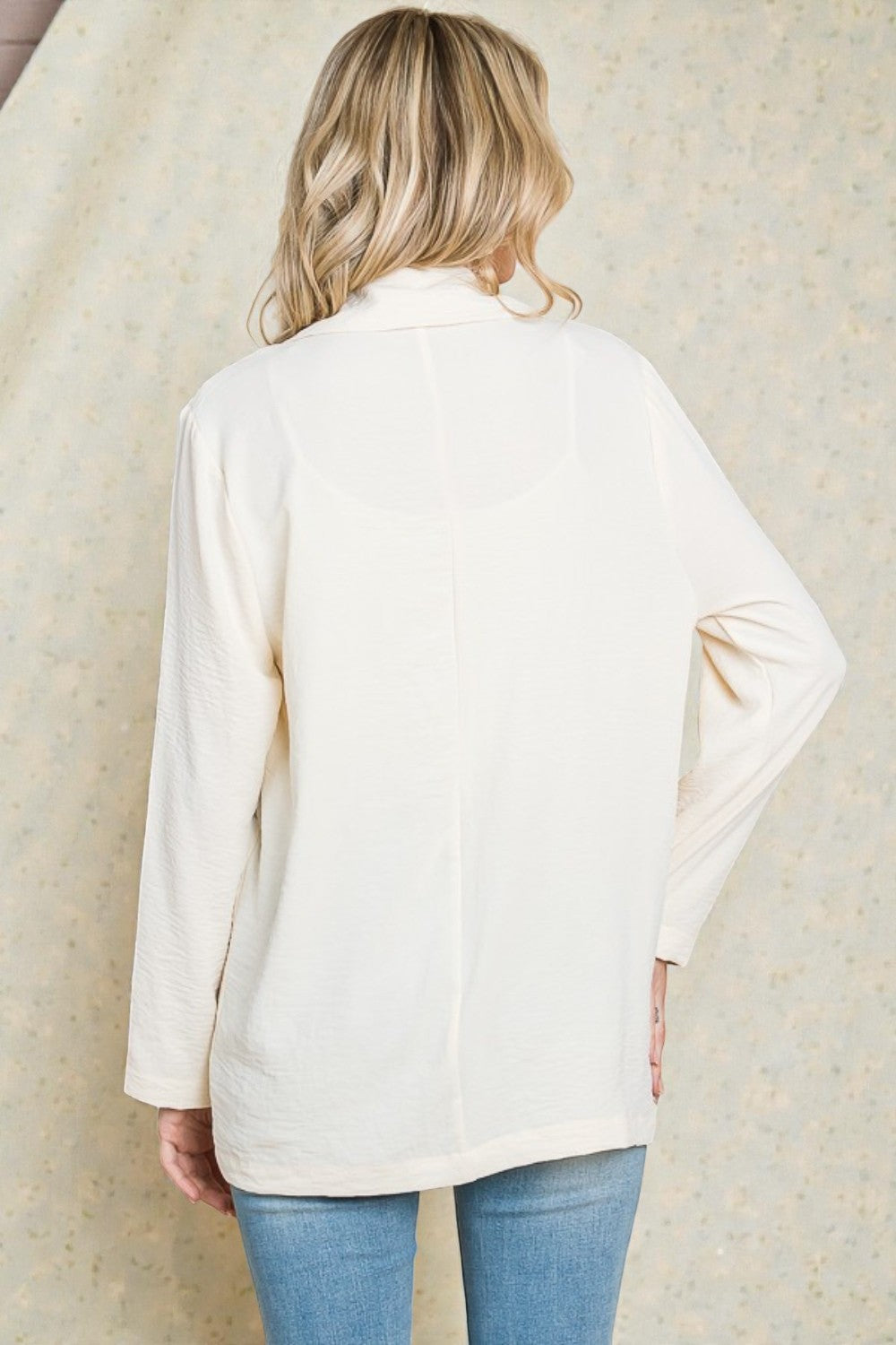 Person wearing a cream-colored cardigan against a neutral background