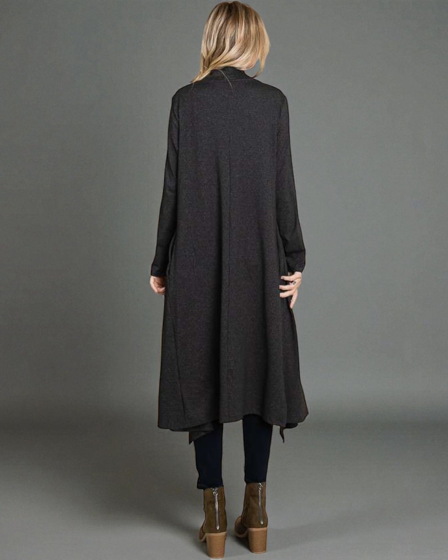 Person wearing a long dark coat on a gray background