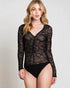 Woman wearing a black sheer long-sleeve bodysuit against a plain background