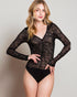 Woman wearing a black sheer long-sleeve bodysuit against a plain background