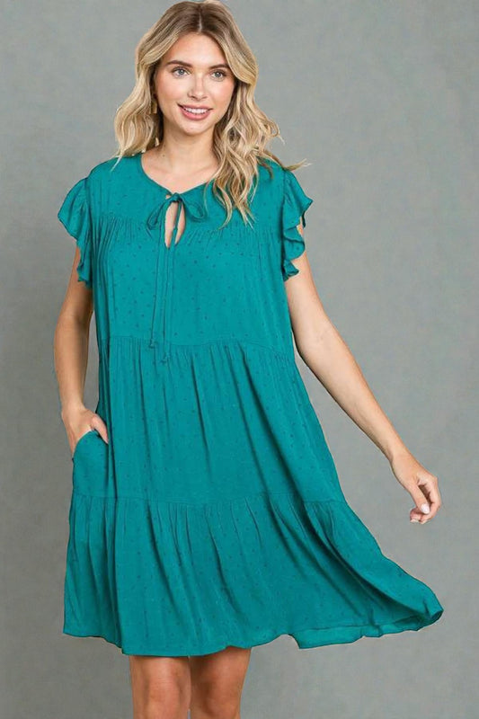 Woman wearing a teal dress against a gray background