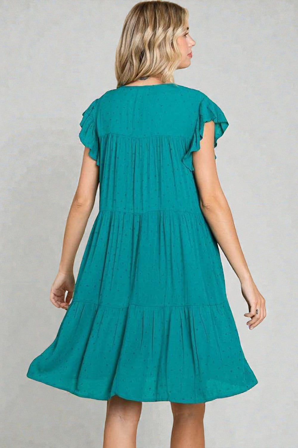 Woman wearing a teal dress against a gray background