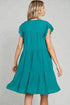 Woman wearing a teal dress against a gray background